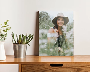 Foto einer Frau mit Hut in Blumenfeld auf Kommode stehend